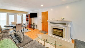 A living room with a fireplace, a dining area, and a television mounted on the wall. - 4 Mi to Dtwn: Pet-Friendly Home in Utica (Utica)