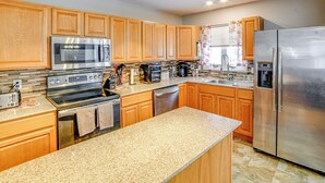 A modern kitchen with wooden cabinets, stainless steel appliances, granite countertops, and a large island. - 4 Mi to Dtwn: Pet-Friendly Home in Utica (Utica)