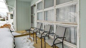A covered porch with four metal chairs, a window with frosted glass, and a snow-covered ground. - 4 Mi to Dtwn: Pet-Friendly Home in Utica (Utica)