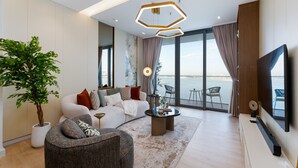 A modern living room with a sofa, armchair, coffee table, and a large potted plant. - Premium 2BR Emaar Beachfront w/ Beach Access (Dubai)