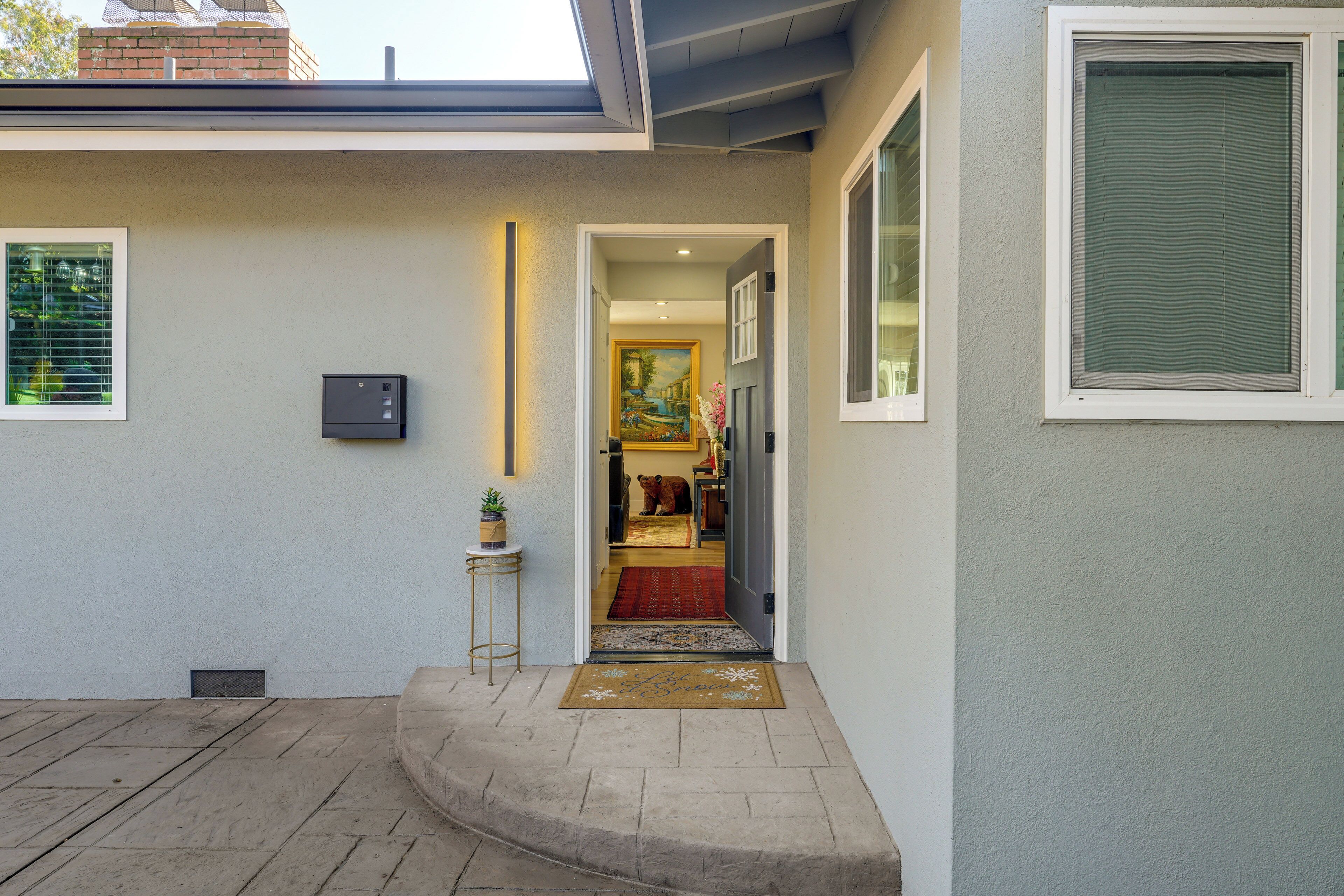 Una entrada de casa moderna con vista despejada al interior, una mesita lateral con una planta y un felpudo.