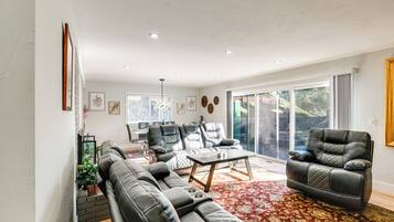 A modern living room with a sectional sofa, a leather armchair, and a coffee table. There is a large window with a view of the outdoors.