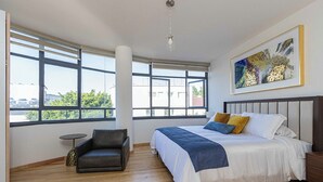 Ein Schlafzimmer mit einem großen Bett, einem Sessel, einem kleinen Tisch und einem Bild an der Wand.