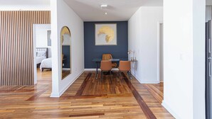 Ein modernes Interieur mit Holzboden, einem Essbereich mit Stühlen, einem Tisch und einem Wandbild.