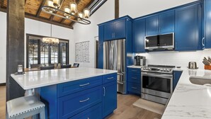 A modern kitchen with blue cabinets, stainless steel appliances, and a large island. - Luxury home near Mt Rushmore!  King beds in 3 of 4 bedrooms!  (Keystone)