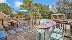 Una terraza de madera con mobiliario exterior, una piscina y un pabellón.