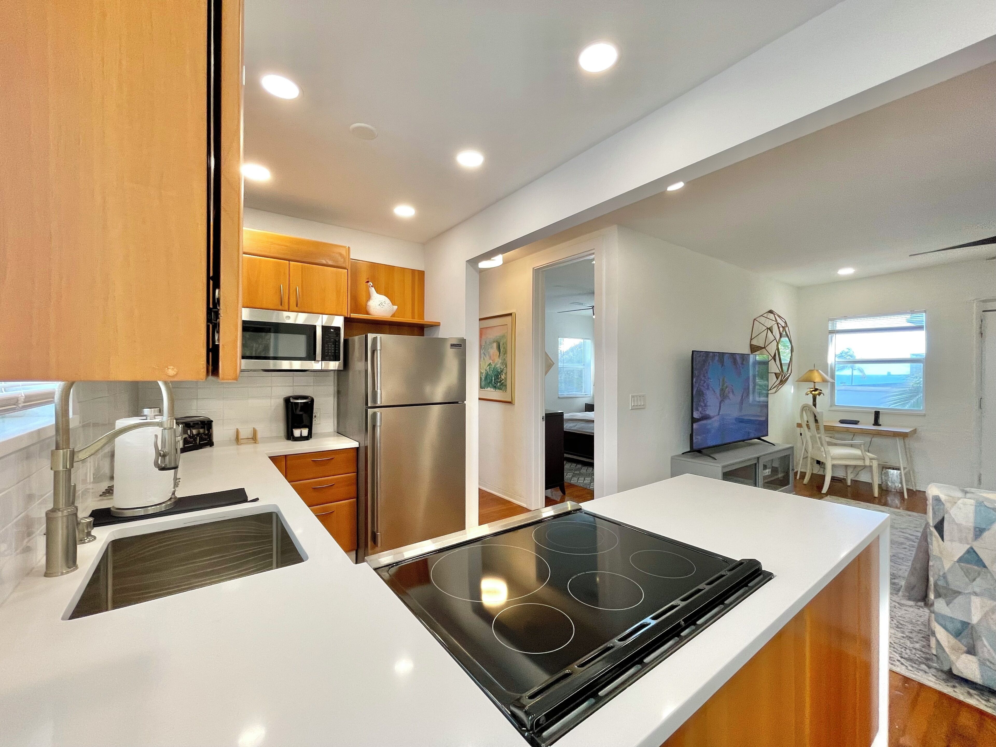 A modern kitchen with a built-in stove, microwave, and refrigerator, leading to a dining area with a view.