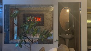 A bathroom with a marble wall, a neon sign, a mirror, and a sink.