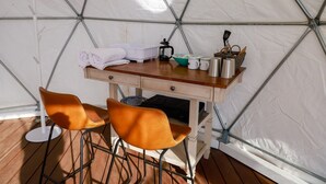 A tent with a wooden table, two chairs, and various kitchen items. - A Cozy Fireside Glamping Escape with Ridge Views (Fallbrook)