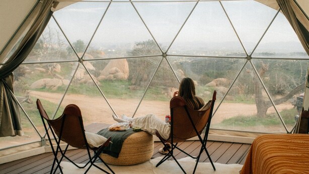 A cozy tented room with a view of a rocky landscape. There are two chairs and a small table with a blanket. - A Cozy Fireside Glamping Escape with Ridge Views (Fallbrook)