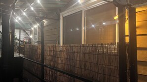 Un espacio al aire libre cubierto con cerca metálica, ventana y pared de madera.
