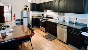 Una cocina moderna con armarios oscuros, electrodomésticos de acero inoxidable y una mesa de comedor de madera.