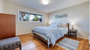 A bedroom with a bed, bedside lamps, a window, and artwork on the wall. - Spacious yet cozy 3-BR home in lovely SE Eugene near University of Oregon (Eugene)