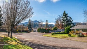 A residential street with houses, a stop sign, and a mountain in the background. - Spacious yet cozy 3-BR home in lovely SE Eugene near University of Oregon (Eugene)
