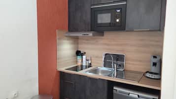 Una cocina compacta con microondas, lavaplatos y fregadero.