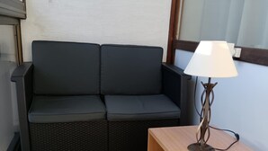 A room with a dark grey sofa, a wooden side table with a lamp, and a patterned floor. - The groundhog (La Bresse)