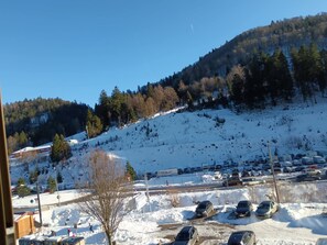 A parking lot with several cars and a snow-covered hill in the background. - The groundhog (La Bresse)