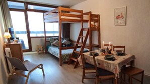 A room with a bunk bed, a dining table set for two, and a view of the sea through large windows. - The groundhog (La Bresse)