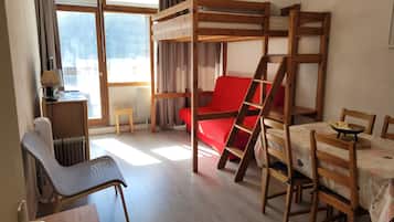 Una habitación con una cama individual superpuesta, un escritorio con una silla, un radiador y una ventana con cortinas.