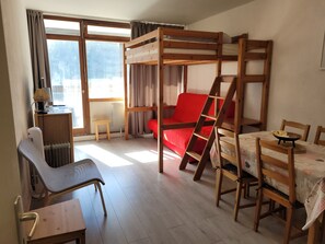A room with a bunk bed, a desk with a chair, a radiator, and a window with curtains. - The Groundhog   (La Bresse)