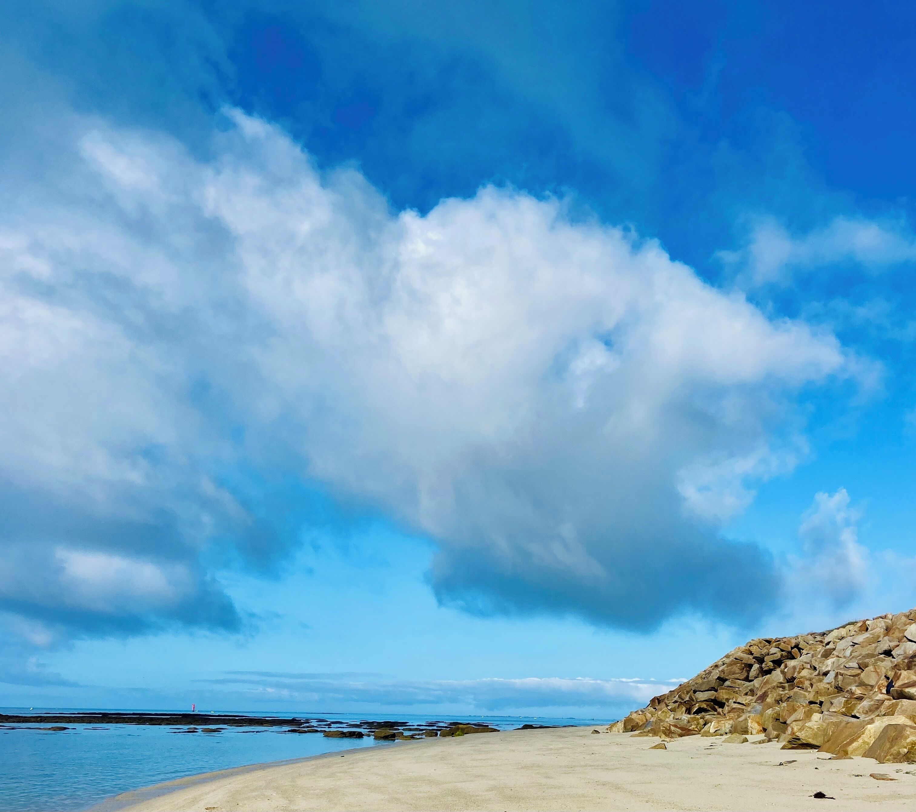 Una playa con un promontorio rocoso y cielo despejado.