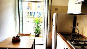 Une cuisine compacte comprenant un coin repas, un réfrigérateur, une cuisinière et une plante en pot.
