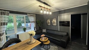 Una sala de estar moderna con un sofá de cuero negro, una mesa de centro de madera y una lámpara colgante.