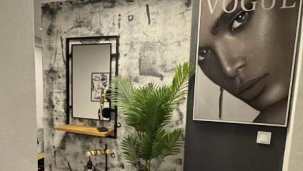 Un interior moderno con una pared de piedra, un espejo, una planta y un cartel de 'Vogue'.