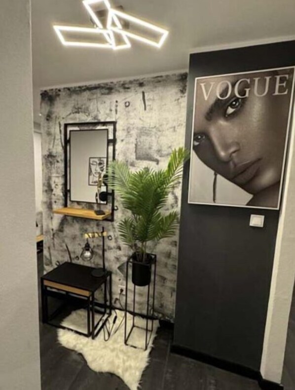 A modern interior with a stone wall, a mirror, a plant, and a 'Vogue' poster. - Apartment DEKO, Town Centre by main Square! (Banskobystrický kraj)
