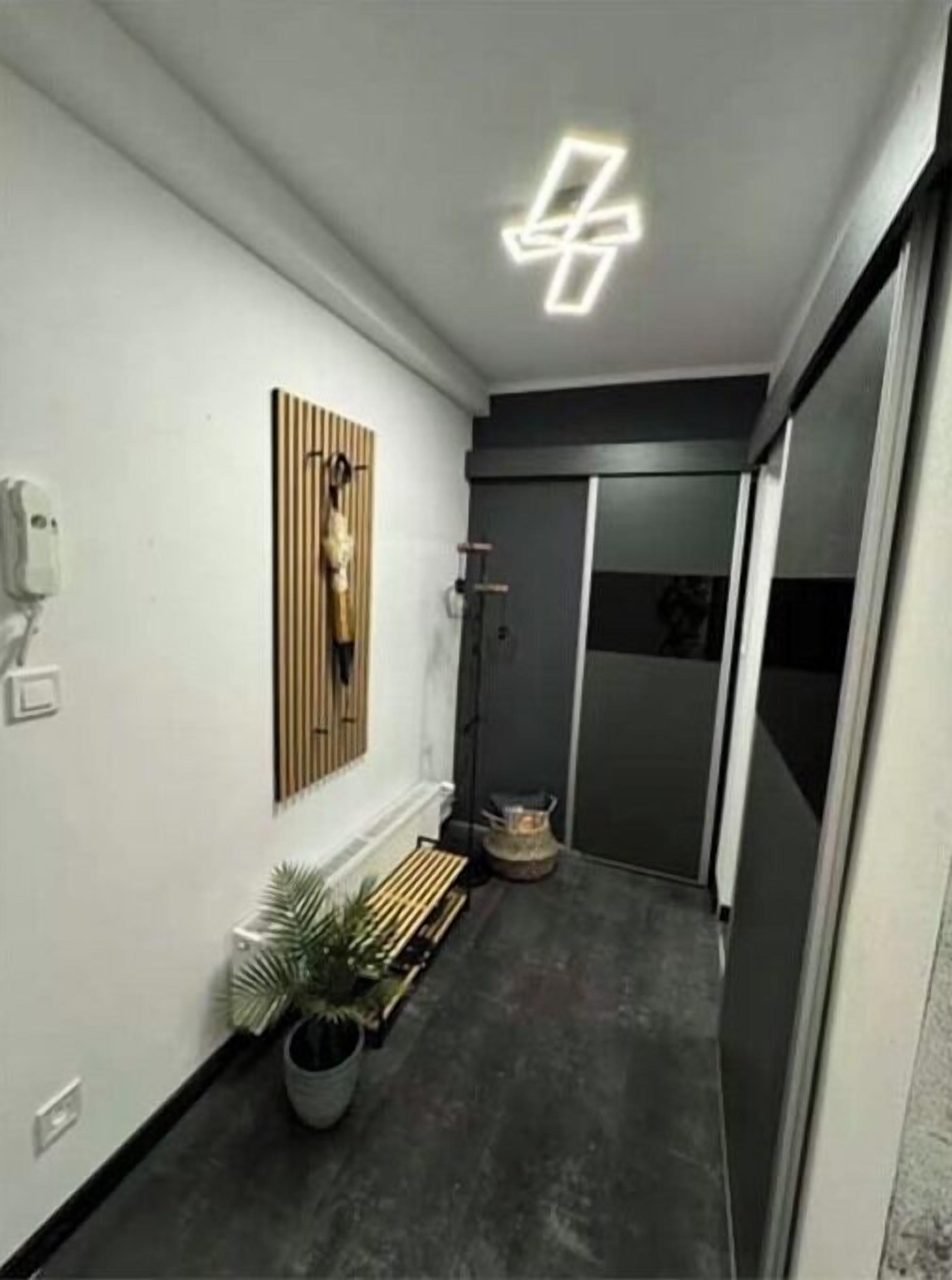 Un couloir avec un banc, un luminaire fixé au mur et une plante en pot.