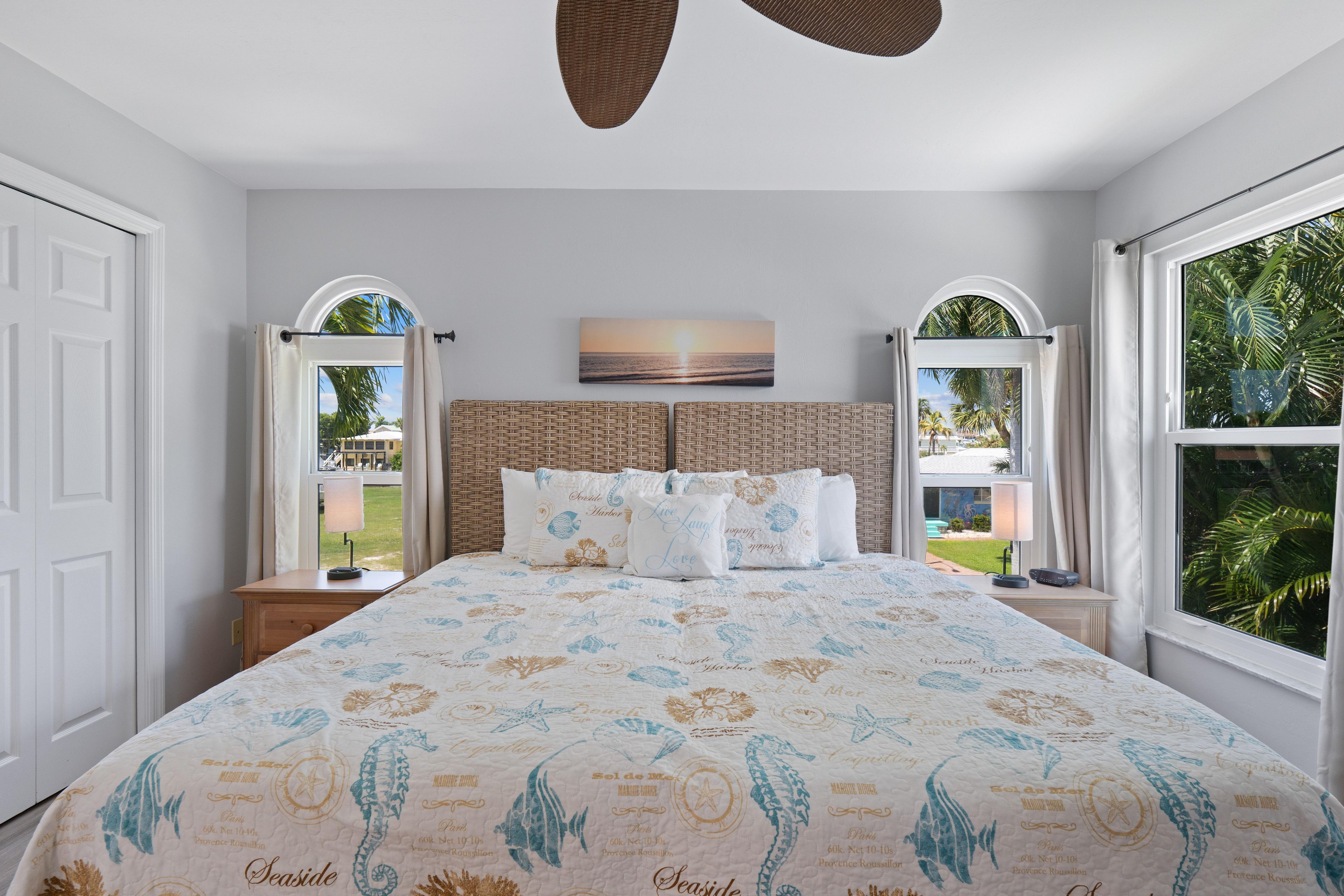 Une chambre à coucher avec un grand lit, deux tables de chevet, une fenêtre avec des rideaux et une vue sur l’extérieur.