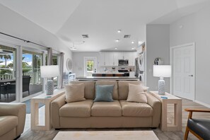 Un salon moderne avec un canapé beige, une table basse et une cuisine en arrière-plan.