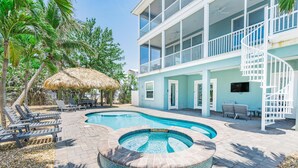 A pool area with lounge chairs, a hot tub, and a building with balconies. - Grande Palermo (Fort Myers Beach)