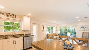 A modern kitchen with a dining area, a view of greenery outside, and a 'Simply Blessed' sign on the wall. - Great Escape-5 (Fort Myers Beach)