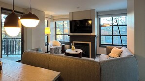Una sala de estar moderna con un sofá, chimenea, televisión y comedor con mesa y sillas.