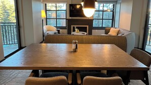 Un comedor con una mesa de madera, cuatro sillas, una lámpara colgante y una chimenea.