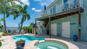 A swimming pool with a hot tub, a covered deck, and a staircase leading to a balcony. - Sea La Vie (Fort Myers Beach)