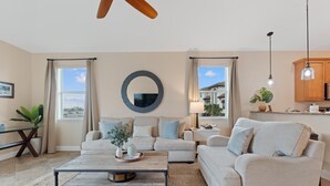 A living room with a sofa, coffee table, and a circular mirror on the wall. - Sea La Vie (Fort Myers Beach)