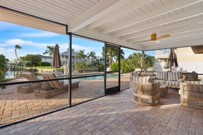 A covered outdoor area with a pool, lounge chairs, and wicker furniture. - Sandy Breeze (Fort Myers Beach)