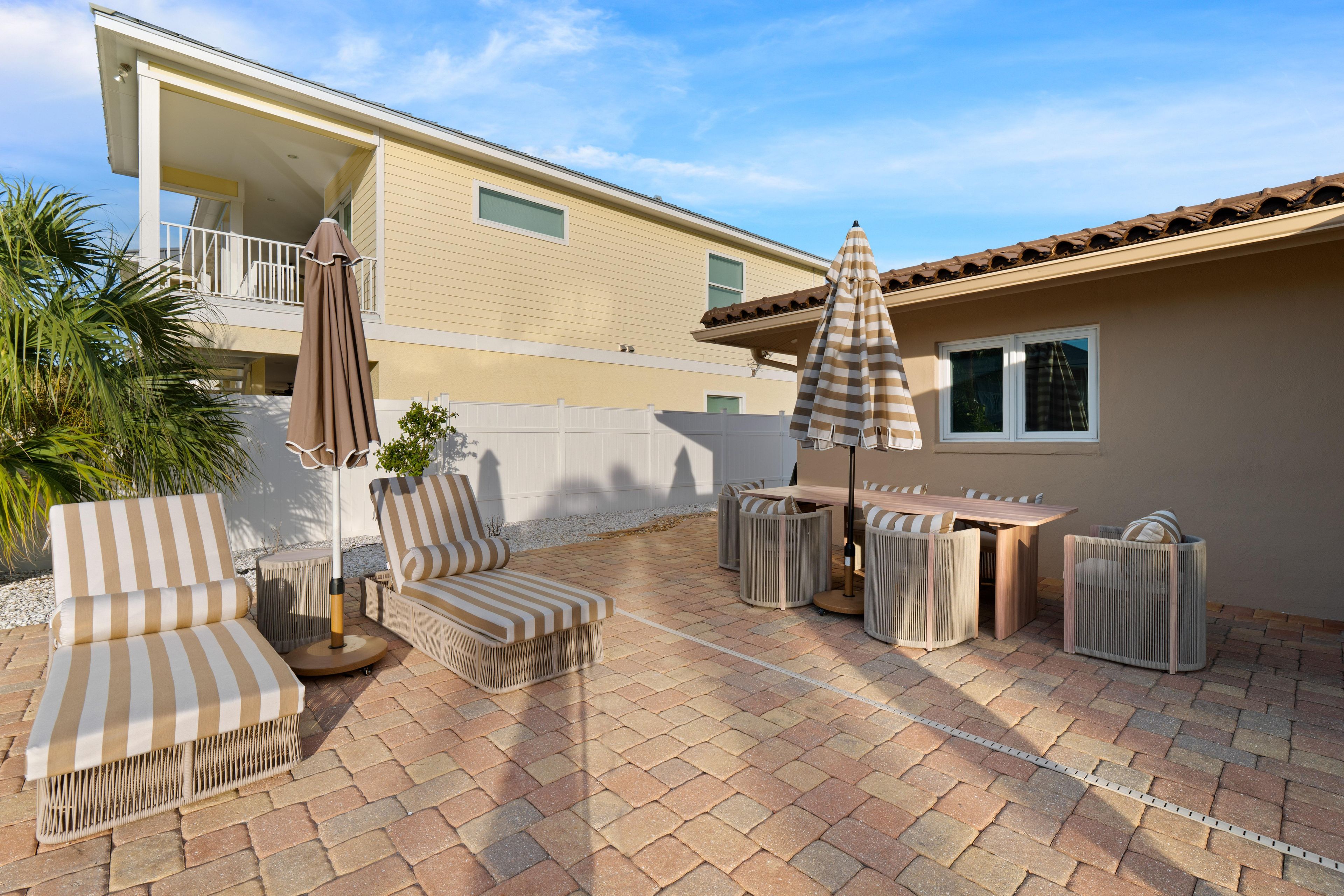 An outdoor patio with striped furniture, a table, and two umbrellas.
