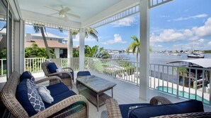 A covered outdoor seating area with wicker furniture and a view of the marina. - Dock Holiday (Fort Myers Beach)