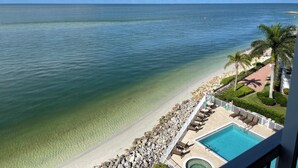 Un resort con vista despejada al océano, piscina y un jardín bien cuidado.