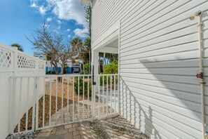 A gated entrance with a white picket fence, a paved pathway, and a clear sky. - Dolphin Dream (Fort Myers Beach)