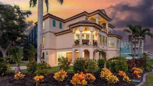 A large, multi-story house with a balcony, surrounded by landscaped gardens with tropical plants. - Sabal Palms (Fort Myers Beach)