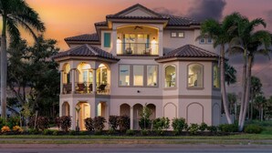 A large, multi-story house with a balcony, arched windows, and a tiled roof. - Sabal Palms (Fort Myers Beach)