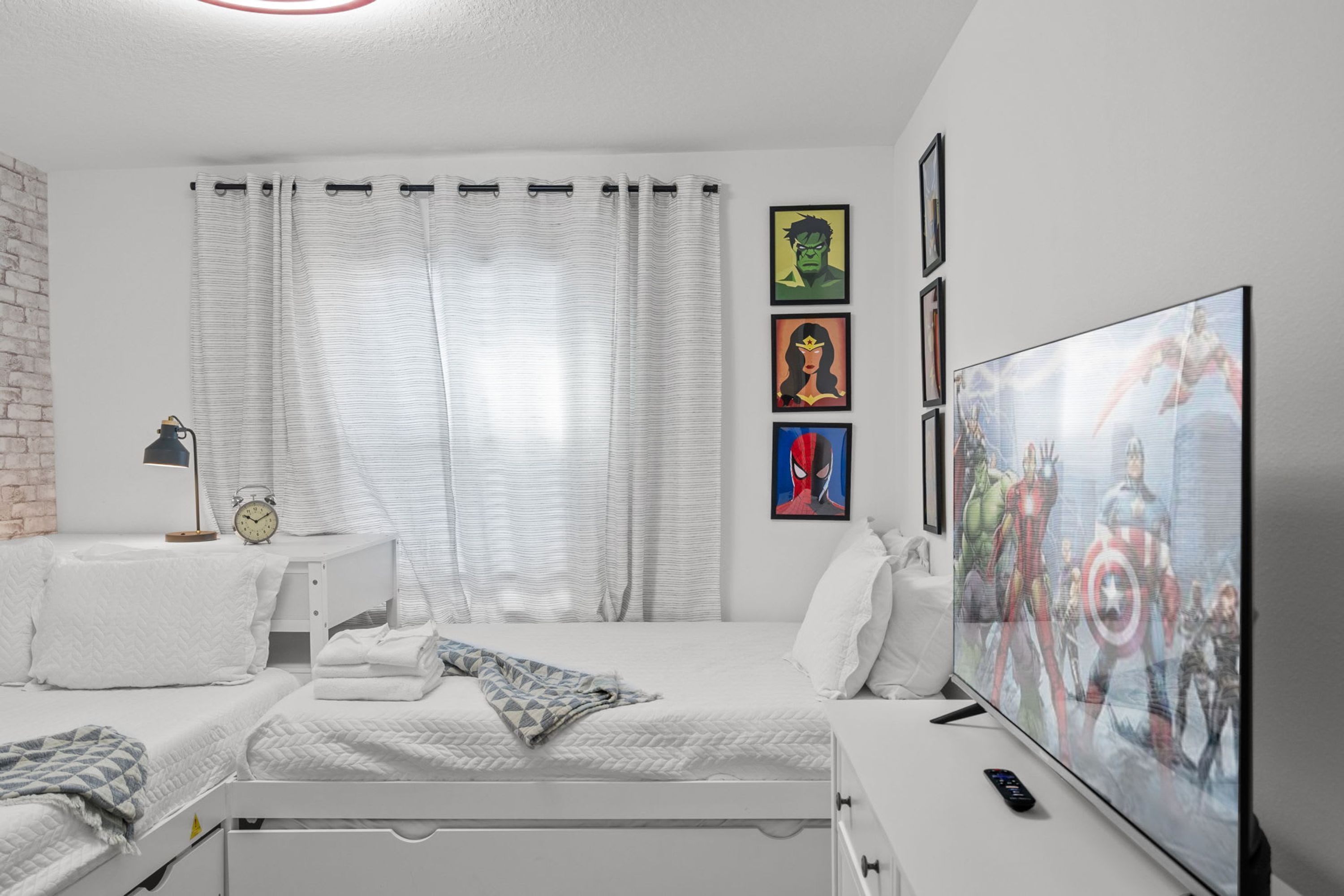 A bedroom with two beds, a TV, and artwork on the wall.