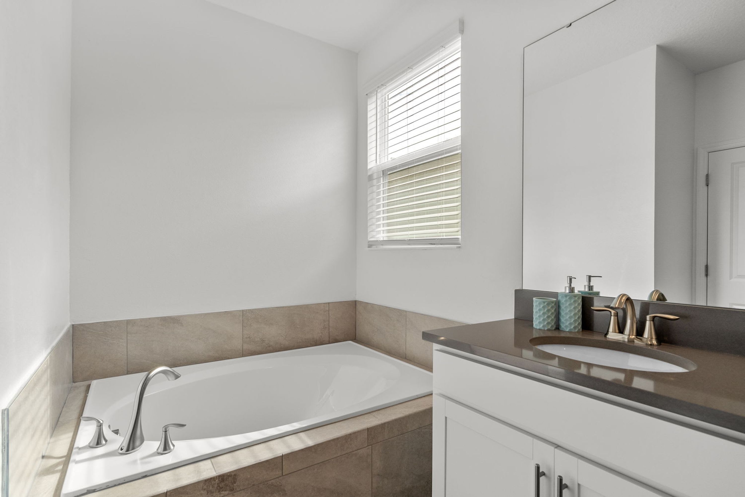 A modern bathroom with a freestanding bathtub, a vanity with a sink, and a large mirror.