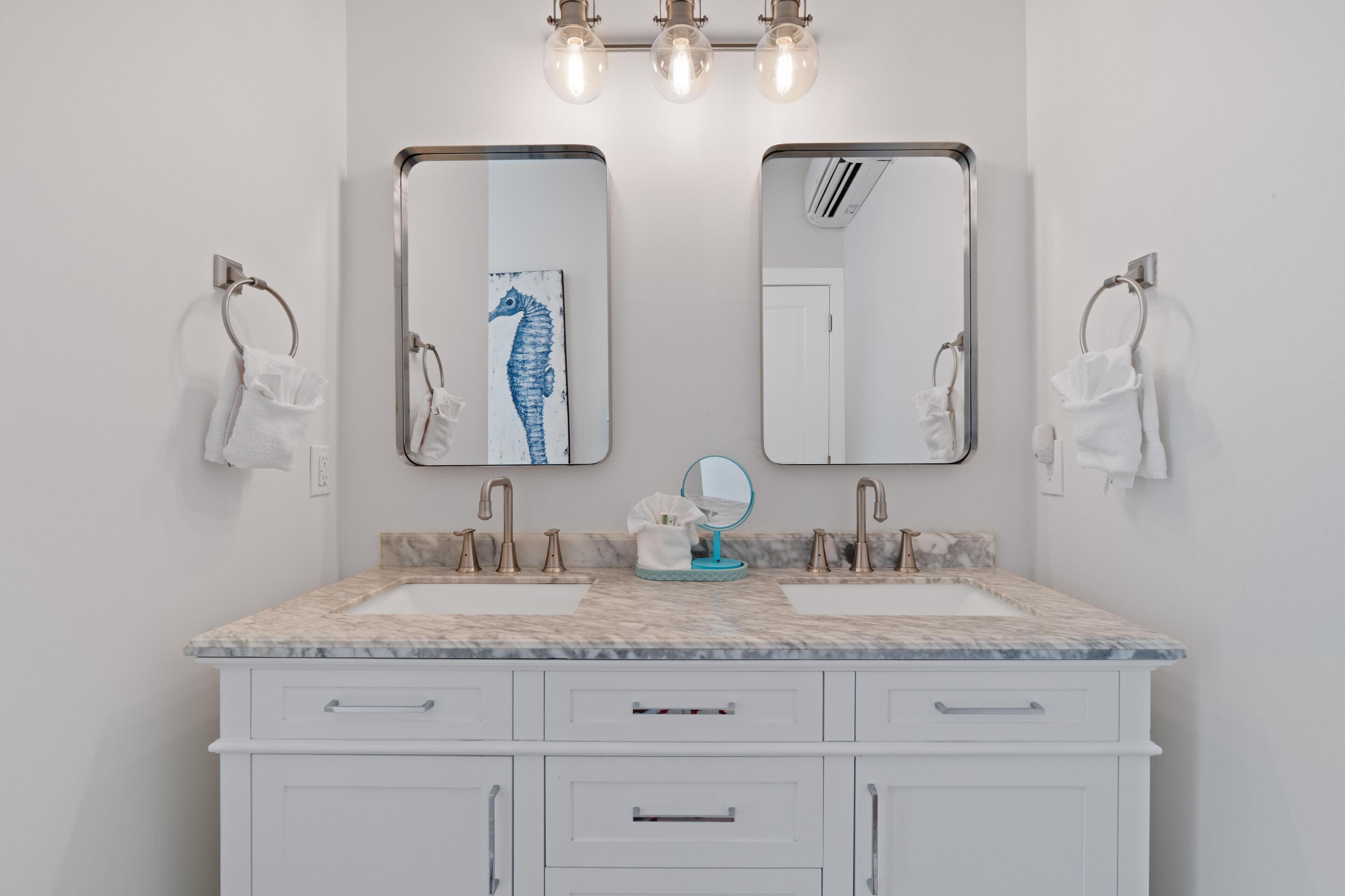 Une salle de bain avec deux lavabos, un miroir et un porte-serviettes.