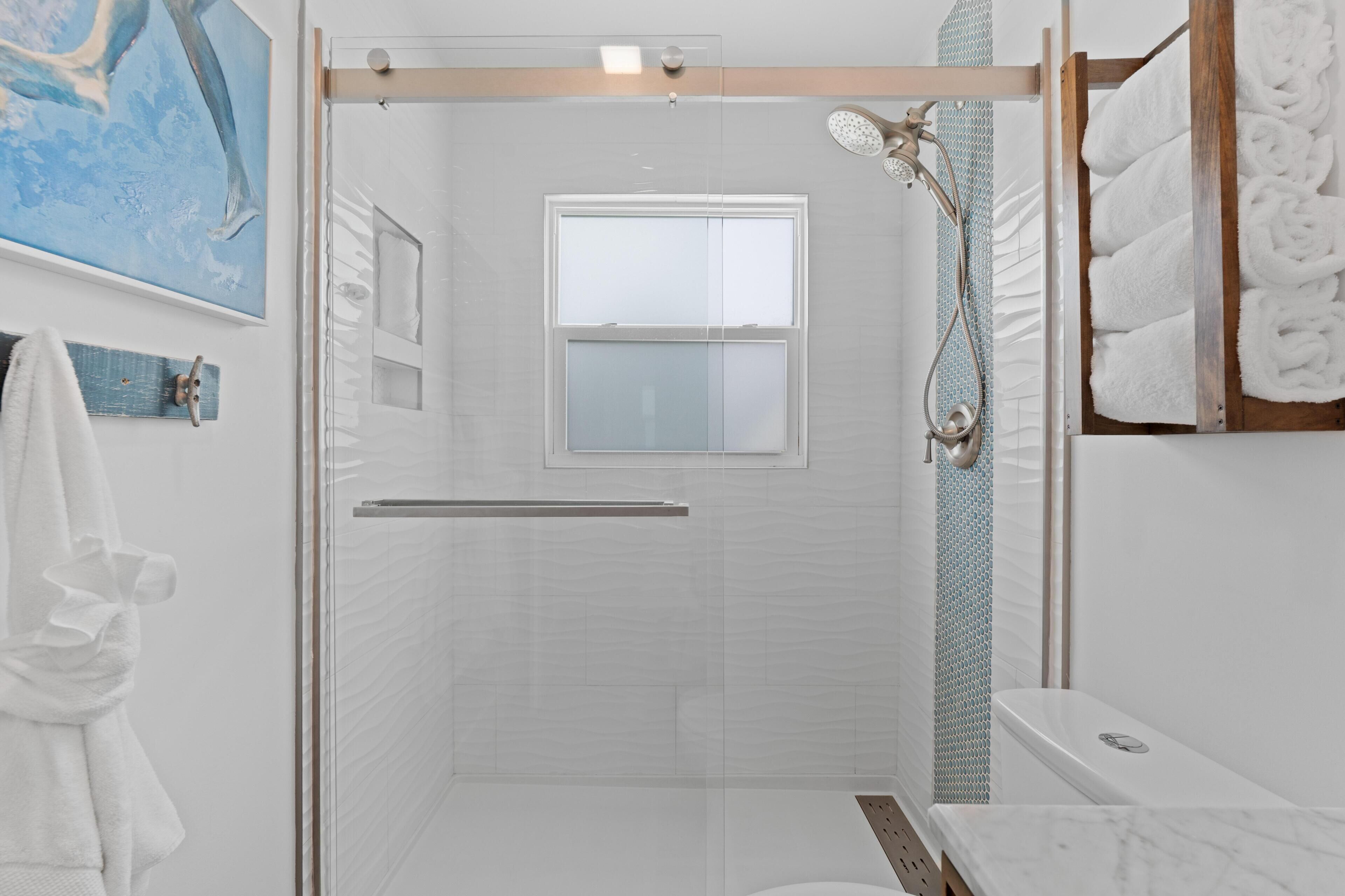 A modern bathroom with a glass-enclosed shower, a toilet, and a towel rack.