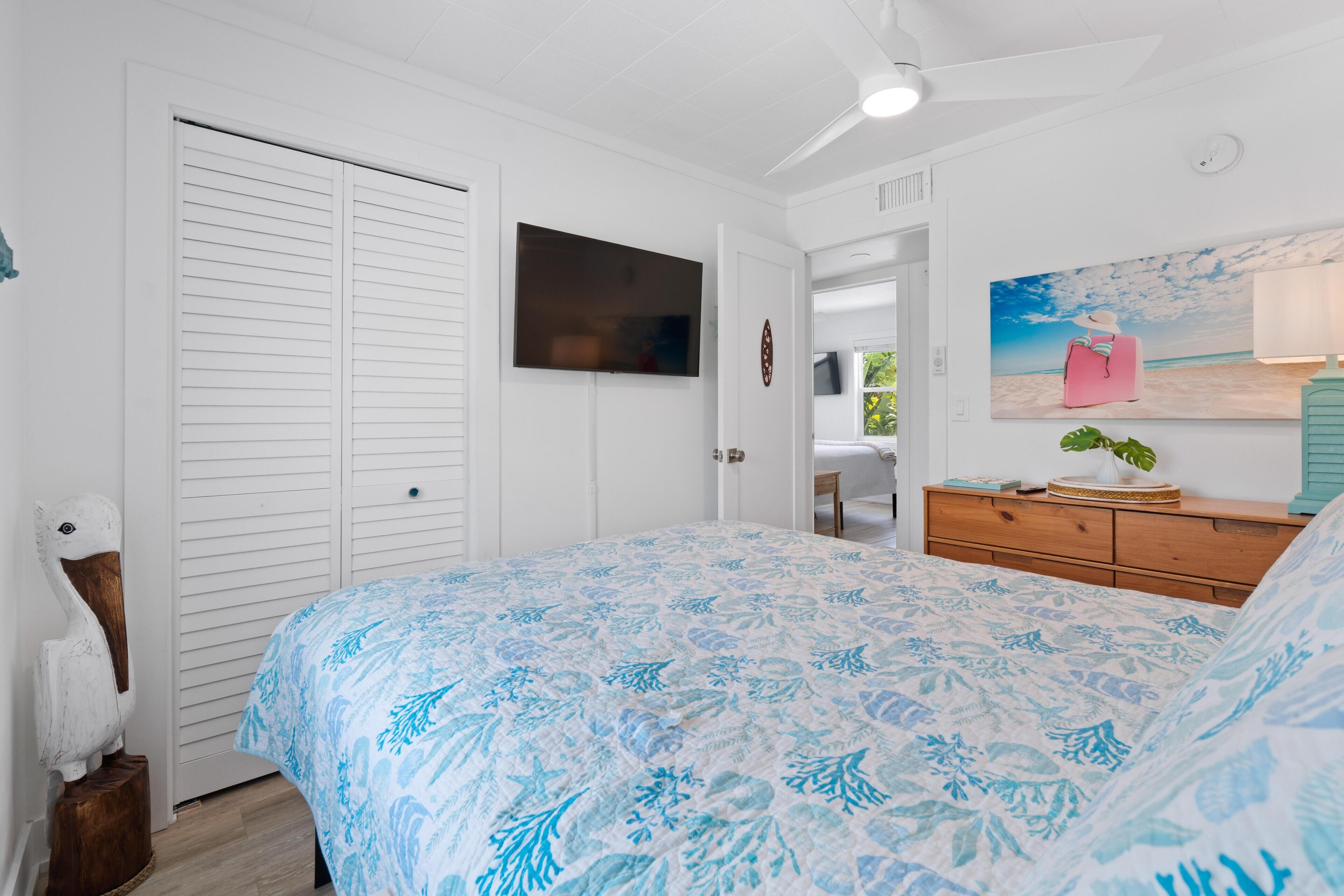 A bedroom with a bed, a TV, a dresser, and a painting.